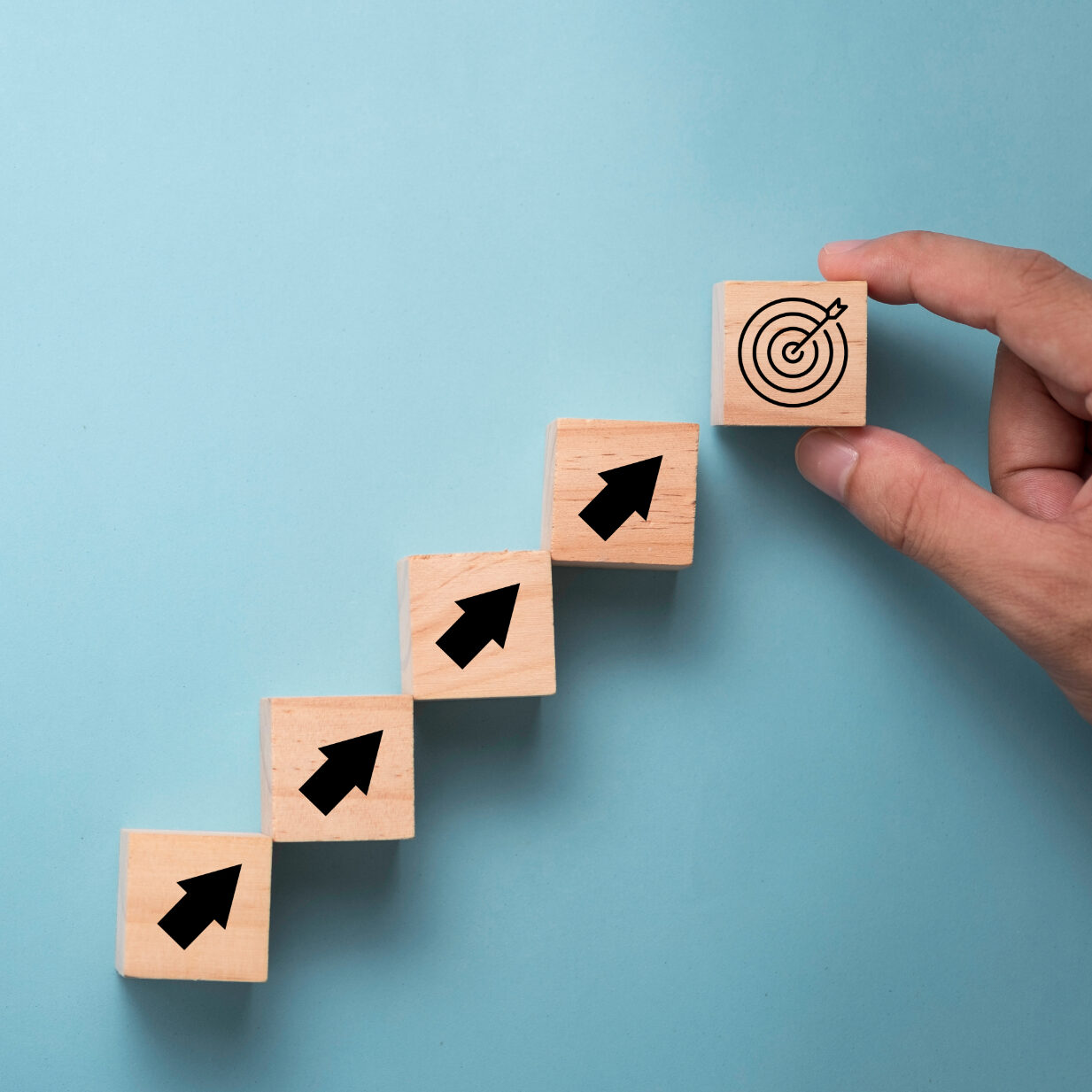 Hand putting virtual target board and arrow which print screen on wooden cube. Business achievement goal and objective target concept.